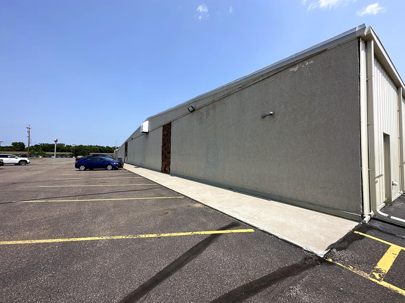 Building exterior with long metal wall and parking lot (Jul 2023)