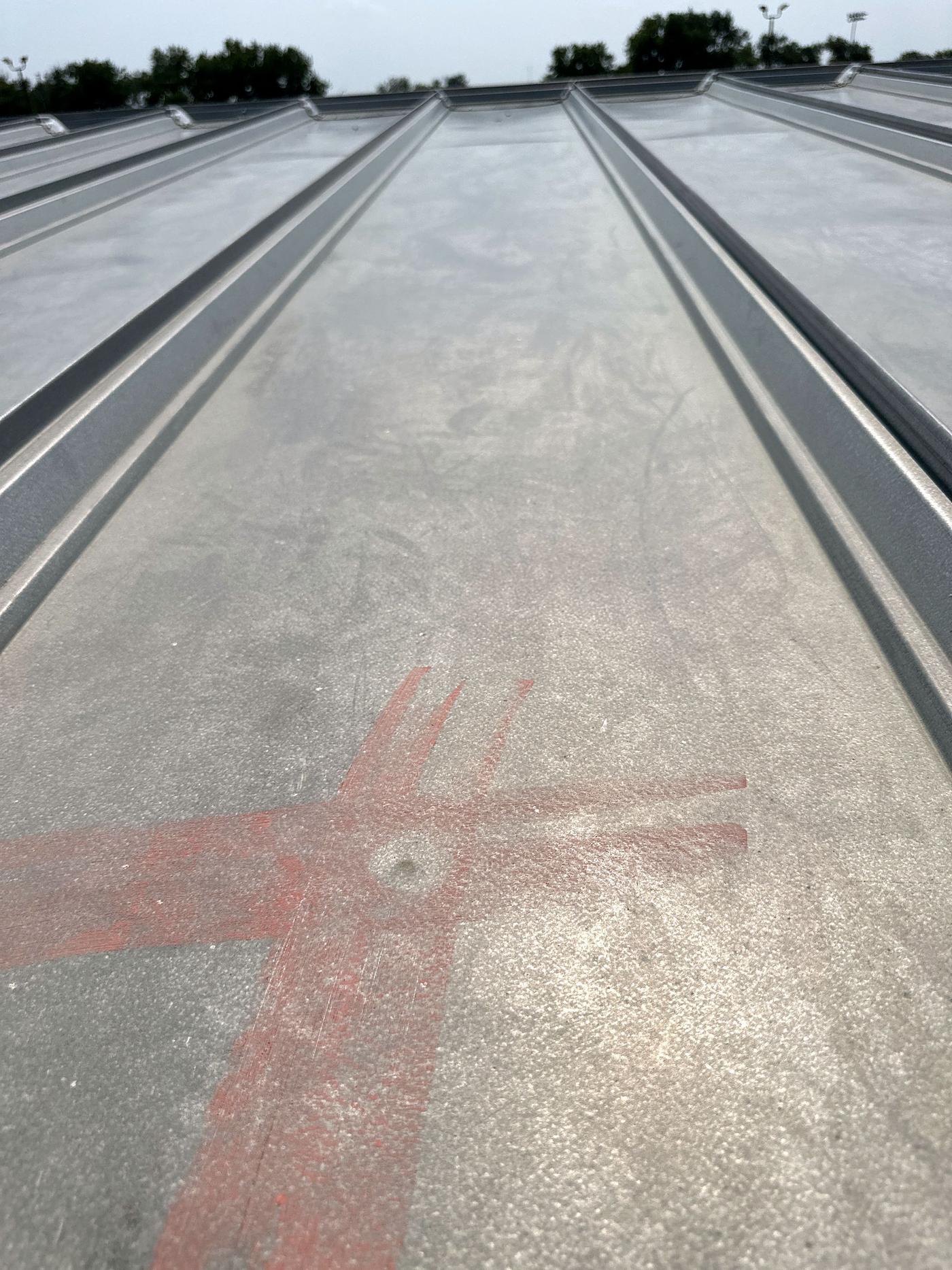 Ribbed metal roof panel with chalk-marked impact (inspection, Jul 2023)